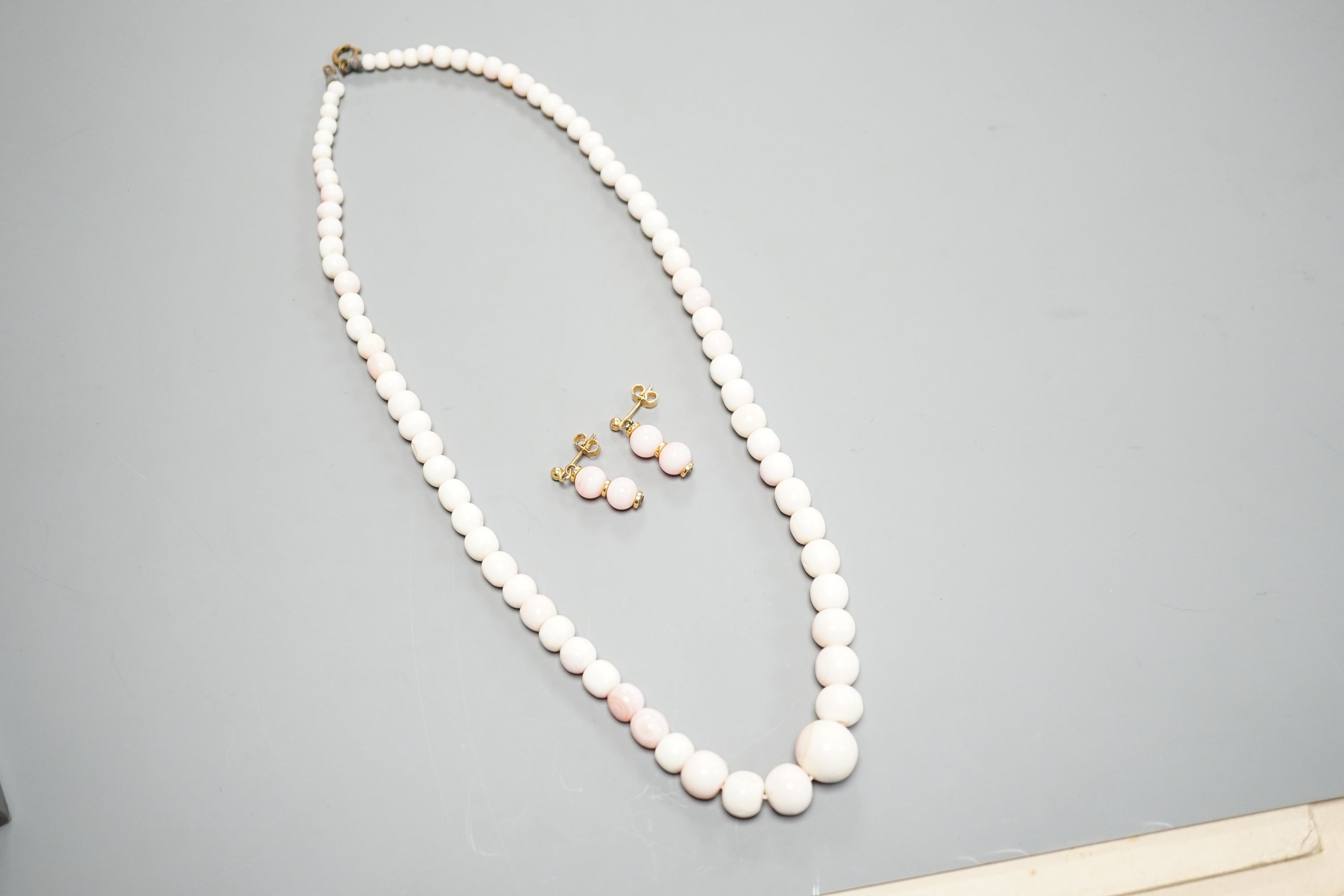 A single strand graduated bleached coral bead necklace, 51cm, gross 43.5 grams and a pair of 750 yellow metal and bleached coral earrings, 24mm, gross 4 grams.